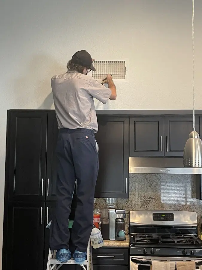 Technician inspecting an air vent during HVAC service in Woodland